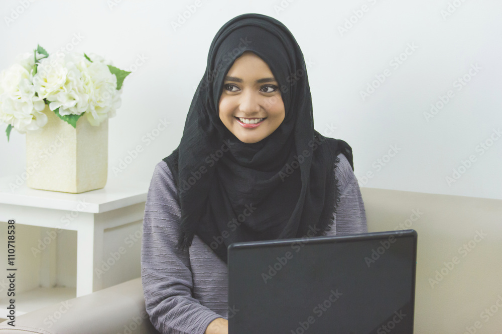 Attractive young woman in head scraf using laptop Attractive young woman in head scraf using laptop