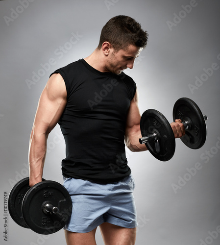 Biceps curl with dumbbell on grey background
