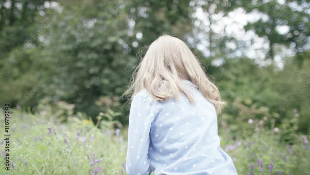  Portrait of pretty smiling little girl picking wildflowers outdoors