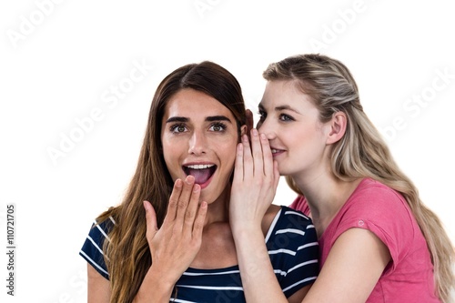 Smiling woman whispering in friend ear 