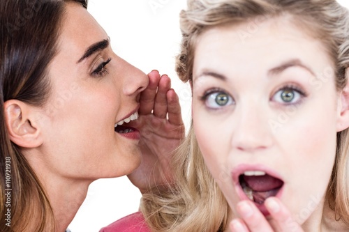 Close-up of woman whispering in friend ear 