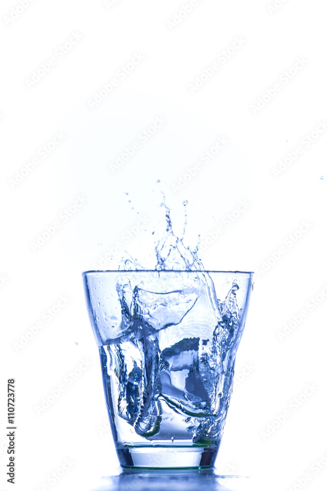 Bicchiere in vetro trasparente isolato su fondo bianco con schizzi e bollicine da fuoriuscita d’acqua Bicchiere in vetro trasparente isolato su fondo bianco con schizzi e bollicine da fuoriuscita d’acqua