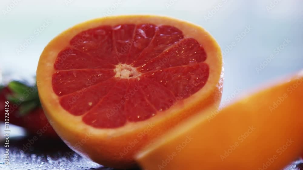 Close up on hands cutting a fresh pink grapefruit into 2 pieces