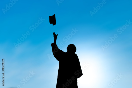Graduates throwing hat on graduation day, silhouette