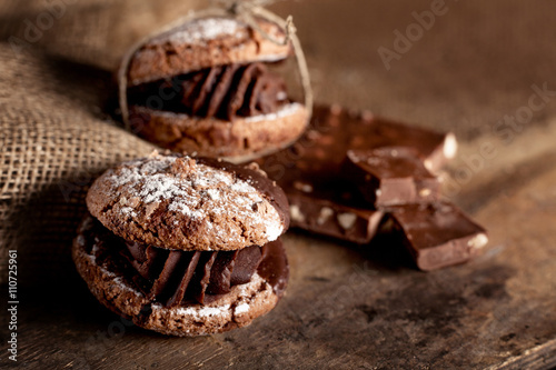 Chocolate cookies with pieces of chocolate on old wooden backgro