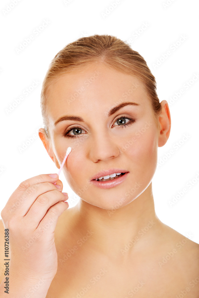 Young woman removing eye makeup with cotton swab Young woman removing eye makeup with cotton swab