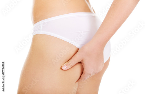 Slim young woman pinching her buttocks