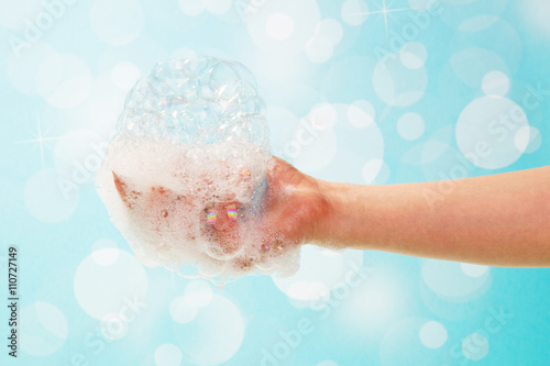 Obraz na plátně Soap and foam in  female hand on abstract blue background.