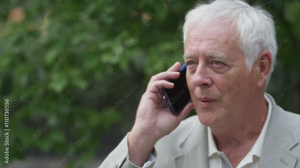 Portrait of happy mature man talking on mobile phone in urban park area Portrait of happy mature man talking on mobile phone in urban park area