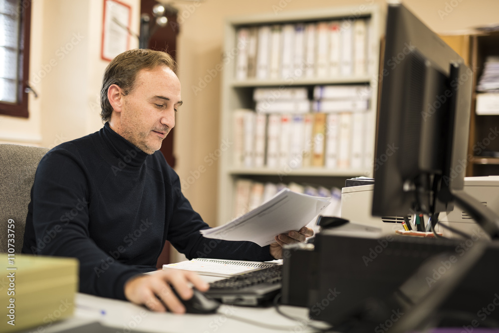 Man looking at document and using pc