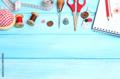 tools tailor spools threads buttons needle sewing  blue wooden background
