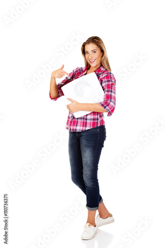 Smiling young woman holding a scale