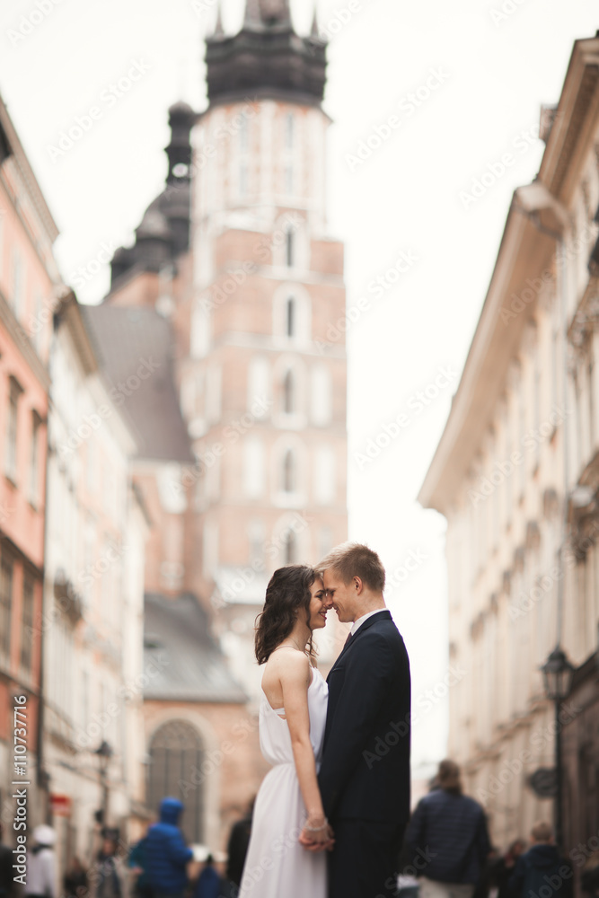 Gorgeous wedding couple, bride, groom kissing and hugging standing in the crowd