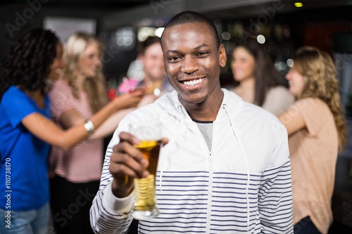 Smiling man showing a beer with his friends