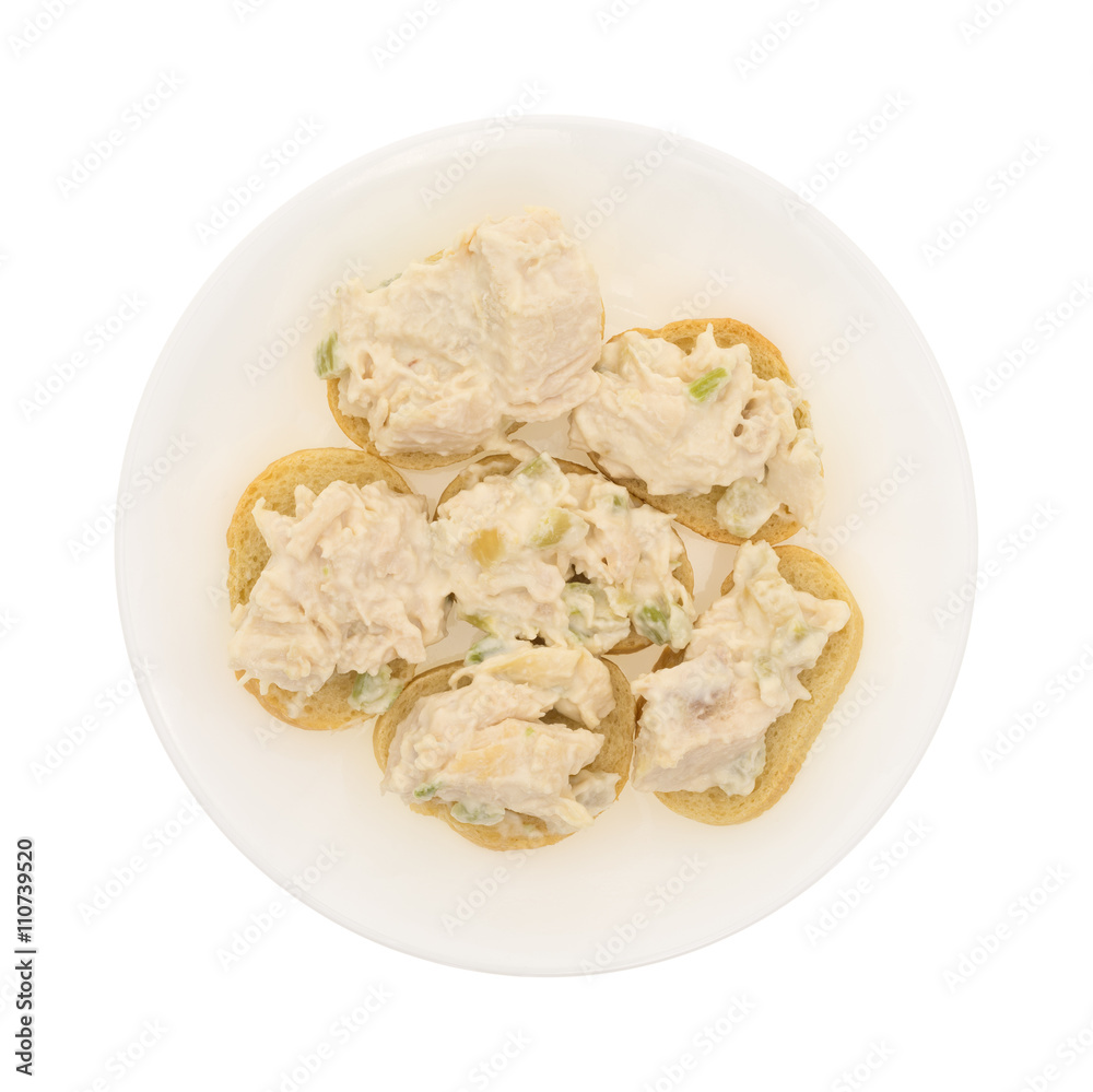 Chicken salad on a small pieces of French bread arranged on a plate isolated on a white background