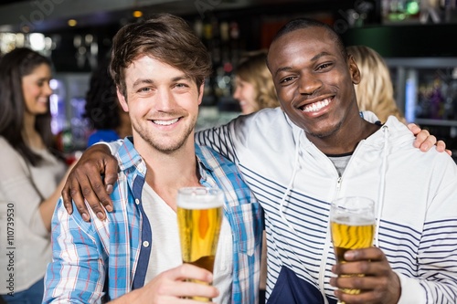 Fototapet Smiling friends showing beer with their friends