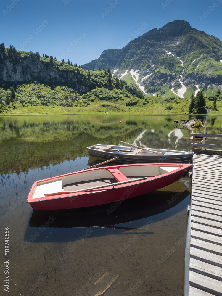 A view of boats that anchor at the bridge of Koerbersee lake around the village Schroecken in Bregenzerwal, region Vorarlberg, Austria