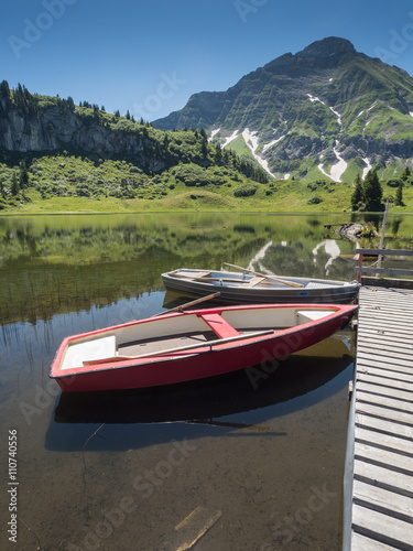 A view of boats that anchor at the bridge of Koerbersee lake around the village Schroecken in Bregenzerwal, region Vorarlberg, Austria