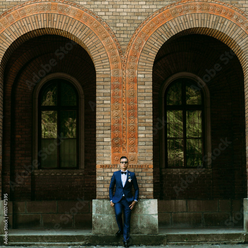 Handsome groom stands next to the arch © IVASHstudio
