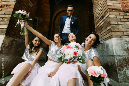 Groom with the charming bridesmaids with the bouquets