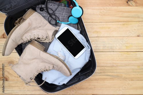 Clothing traveler's Passport, wallet, glasses, watches, smart phone devices, on a wooden floor in the luggage ready to travel.