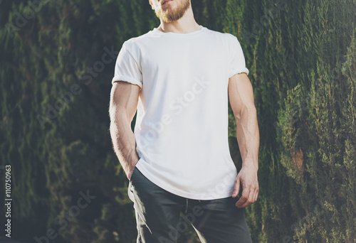 Image Bearded Muscular Man Wearing White Blank t-shirt. Green City Garden Background at sunset. Horizontal Mockup photo