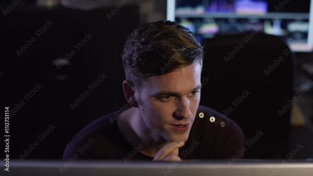  Man working in dark office reacts to something he sees on computer screen