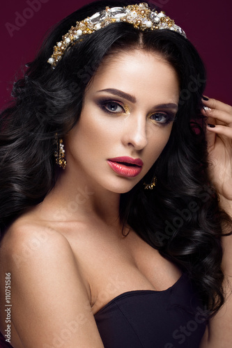 Beautiful brunette model: curls, classic makeup, gold jewelry and red lips. The beauty face. 
