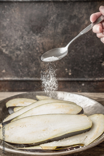 Sprinkling salt on the sliced eggplants vertical