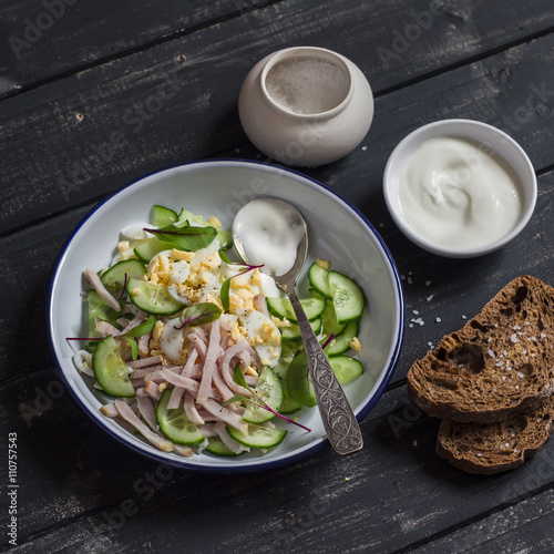 Easy and fast salad with smoked turkey, cucumber and boiled egg on a dark wooden background. Healthy food