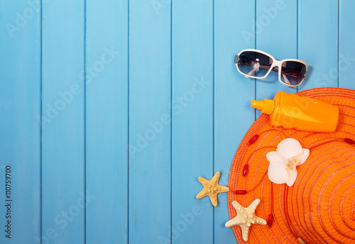 Hat, sunglasses and suntan lotion on wood background colored.