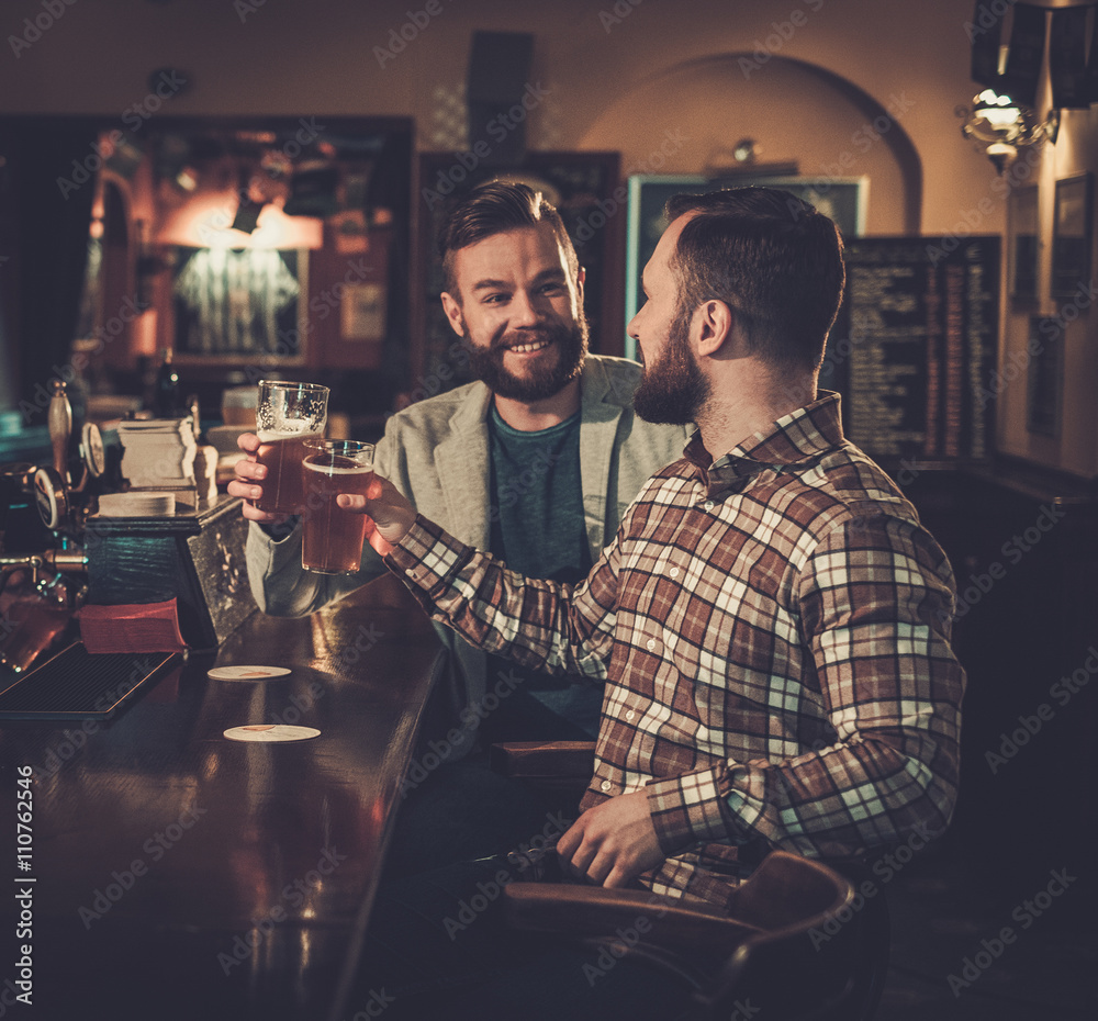 Cheerful old friends having fun and drinking draft beer at bar c