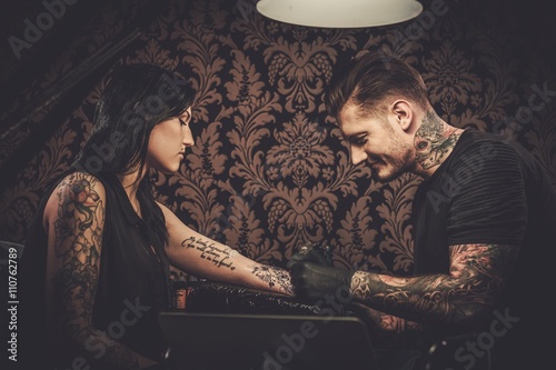 Canvas Print Professional tattoo artist makes a tattoo on a young girl's hand.