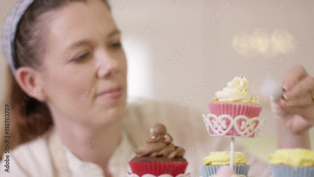 Smiling woman with bakery business putting finishing touches onto cupcakes Smiling woman with bakery business putting finishing touches onto cupcakes