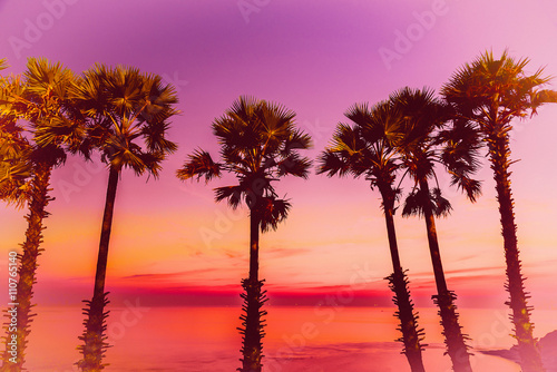 Fototapeta Naklejka Na Ścianę i Meble -  Silhouette coconut palm trees on beach at sunset. Vintage tone.