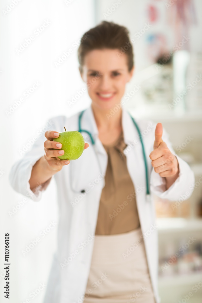 Female doctor giving green apple and showing thumbs up. Closeup Female doctor giving green apple and showing thumbs up. Closeup