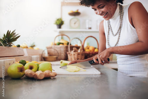 Young woman chopping up fresh fruit for smoothie