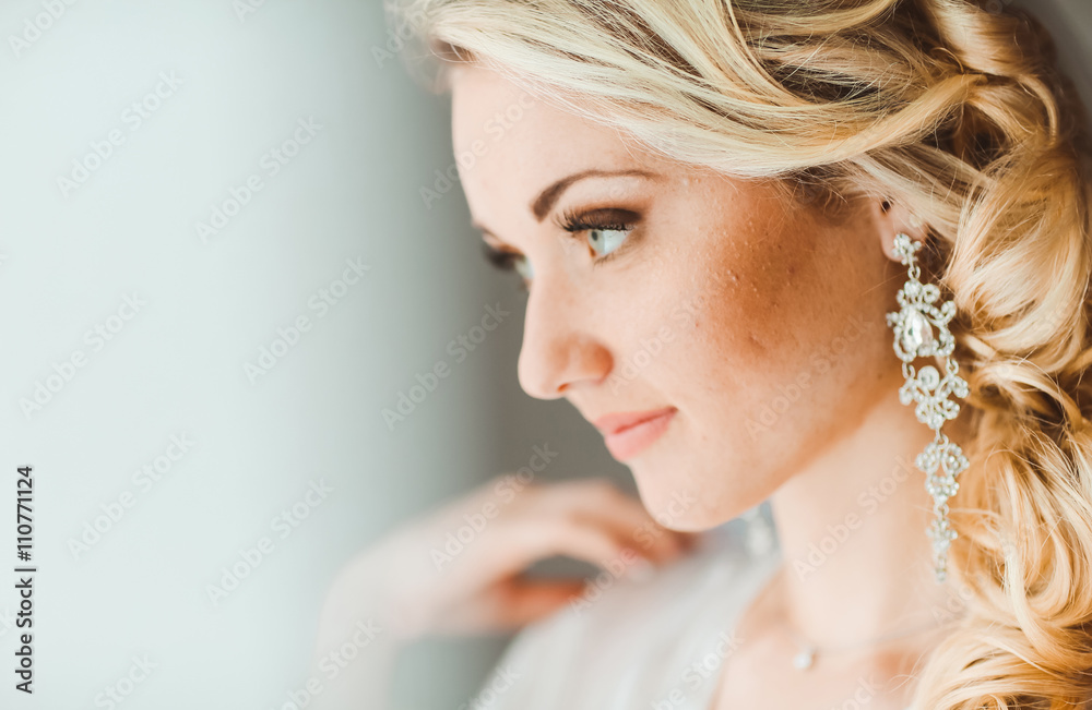 Portrait of beautiful bride with fashion veil posing at home at wedding morning. Makeup. Blondegirl with elegant hair styling. Wedding dress. Close Up