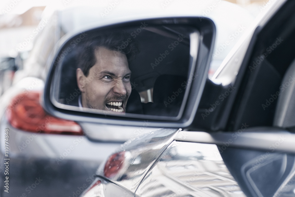 Driver with road rage reflected in wing mirror