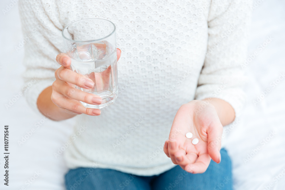 Female hands holding pills and glass with water Female hands holding pills and glass with water
