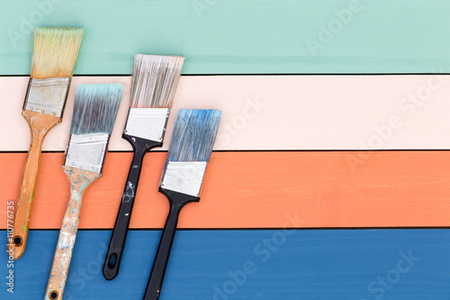 Four paintbrushes over painted wood surface