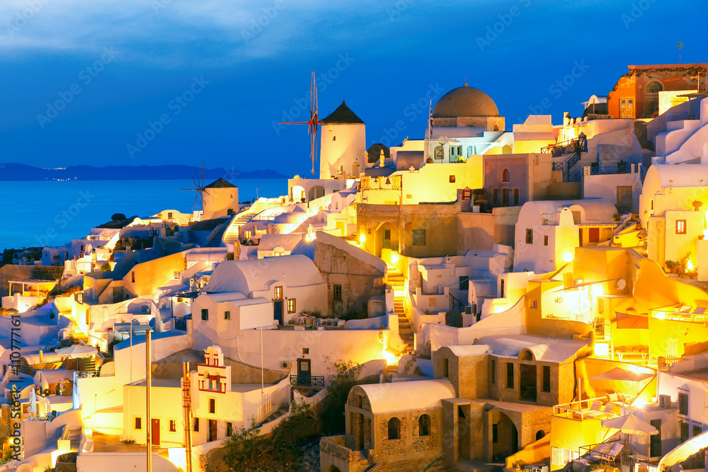Windmills in Oia on the island Santorini, white houses and church during twilight blue hour, Greece