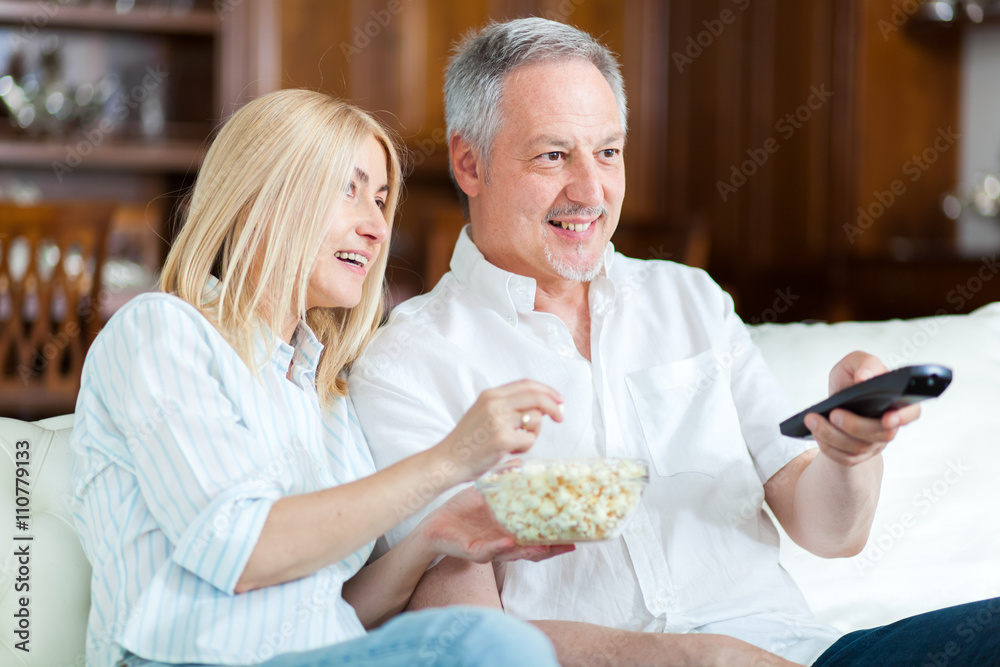  Senior couple sitting in couch and watching tv