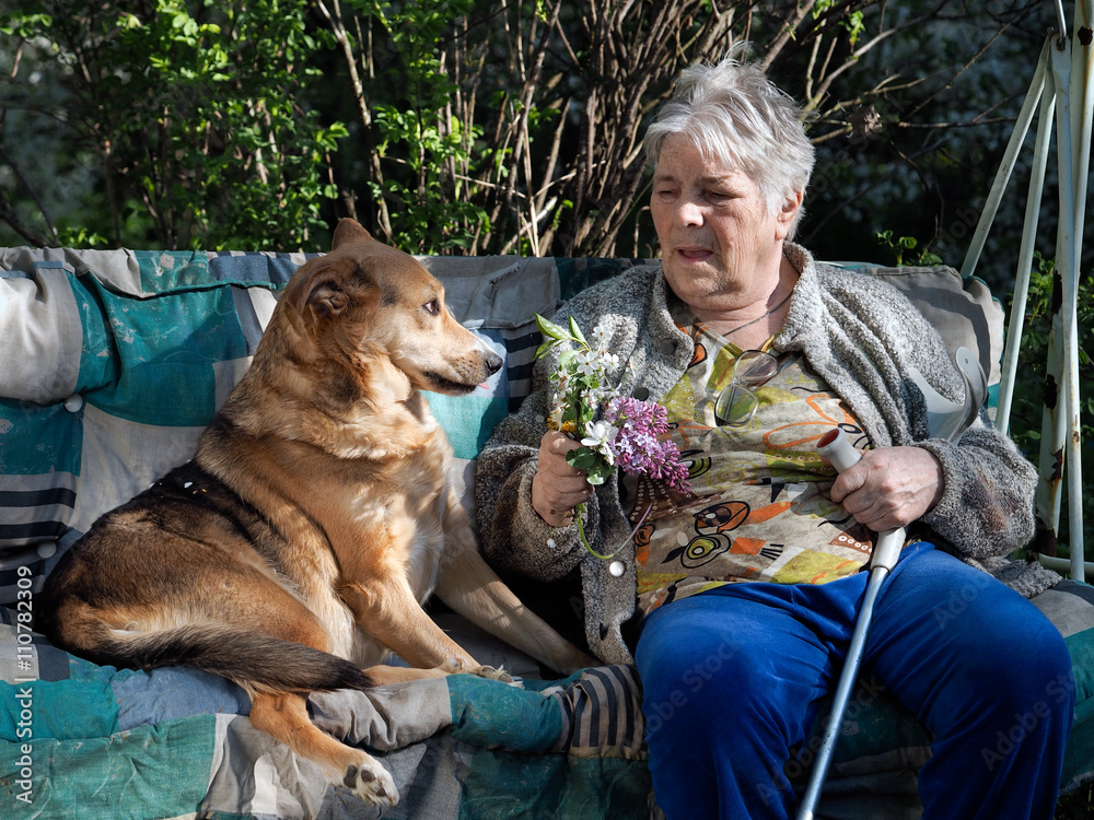 The old lady sitting next to the dog and talking to animals. Grandmother  bouquet of flowers