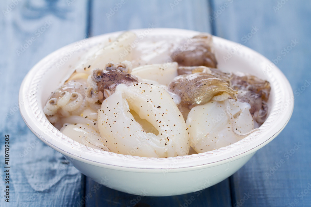 squids in white plate on blue wooden background squids in white plate on blue wooden background