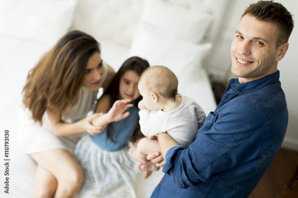 Parents with a little girl and a baby on the bed