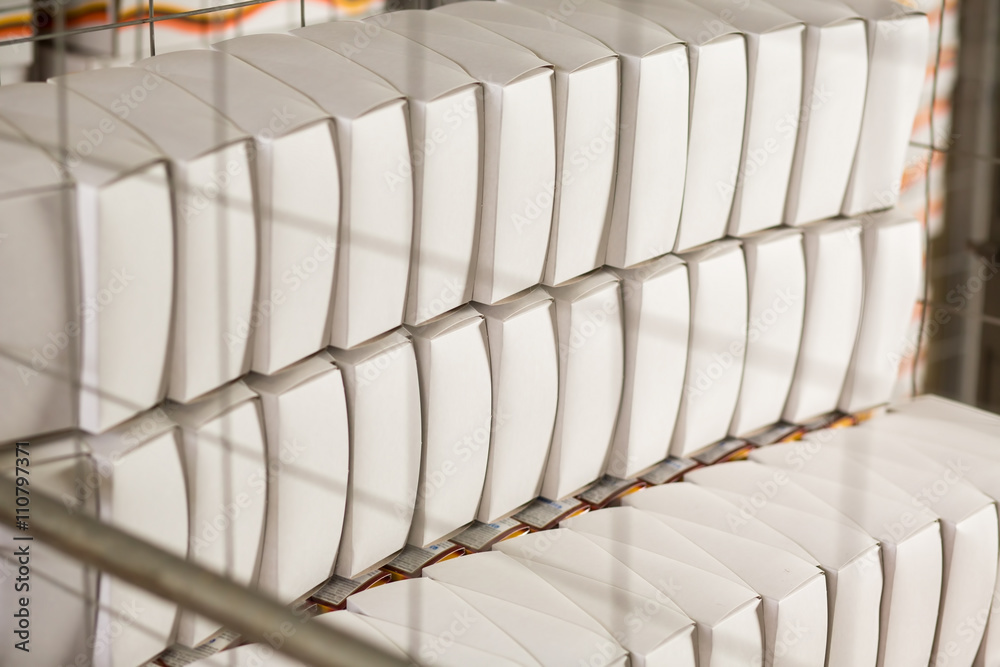 Fototapeta premium White boxes behind grating. Stacks of blank boxes. Product made of recycled material. Safe storage conditions.