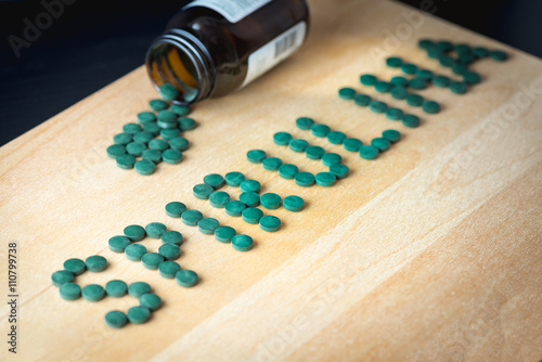 Spirulina supplement pills making up the word spirulina on wooden board and bottle. Antioxidant alga nutrition. photo