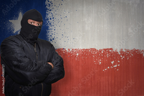 dangerous man in a mask standing near a wall with painted national flag of chile