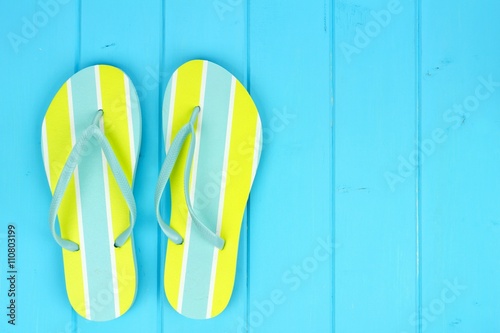 Pair of bright summer flip-flops against a blue wooden background